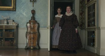 Movie still from “Jane Eyre” (2011), directed by Cary Joji Fukunaga – Two women dressed in period clothing in front of a door; Medium shot, Low angle