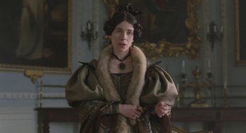 Movie still from “Jane Eyre” (2011), directed by Cary Joji Fukunaga – A woman dressed in renaissance clothing in front of a painting; Medium shot, Low angle