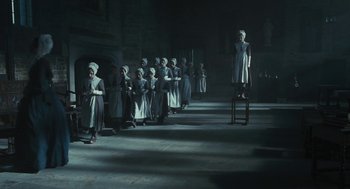 Movie still from “Jane Eyre” (2011), directed by Cary Joji Fukunaga – A group of people standing next to each other in a dark room; Wide shot, Low angle