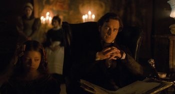 Movie still from “Jane Eyre” (2011), directed by Cary Joji Fukunaga – A man sitting in a chair in front of candles; Medium shot, Over the shoulder angle