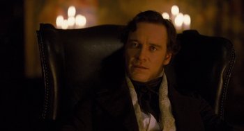 Movie still from “Jane Eyre” (2011), directed by Cary Joji Fukunaga – A person sitting in a chair wearing a suit; Close Up shot, Over the shoulder angle
