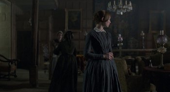 Movie still from “Jane Eyre” (2011), directed by Cary Joji Fukunaga – A woman standing in front of two other women in a room; Medium shot, Over the shoulder angle