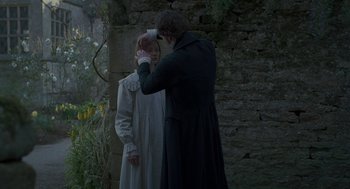 Movie still from “Jane Eyre” (2011), directed by Cary Joji Fukunaga – A man and a woman standing next to each other in front of a stone wall; Medium shot, Over the shoulder angle
