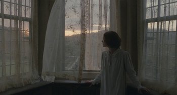 Movie still from “Jane Eyre” (2011), directed by Cary Joji Fukunaga – A woman standing in front of a window looking out; Medium shot, Over the shoulder angle