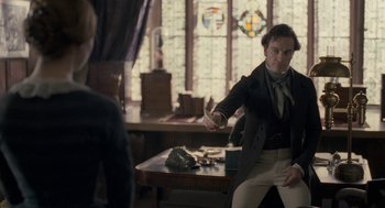 Movie still from “Jane Eyre” (2011), directed by Cary Joji Fukunaga – A man in a black jacket is holding something in his hand; Medium shot, Over the shoulder angle