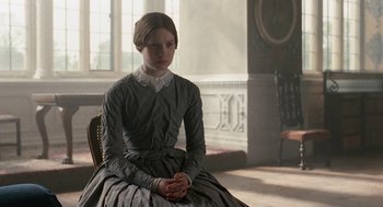 Movie still from “Jane Eyre” (2011), directed by Cary Joji Fukunaga – A woman in a dress sitting on a chair; Medium shot, Low angle