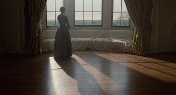 Movie still from “Jane Eyre” (2011), directed by Cary Joji Fukunaga – A woman standing in front of a window in a room; Wide shot, High angle