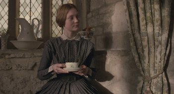 Movie still from “Jane Eyre” (2011), directed by Cary Joji Fukunaga – A young woman holding a cup of tea in her hands; Medium shot, Over the shoulder angle