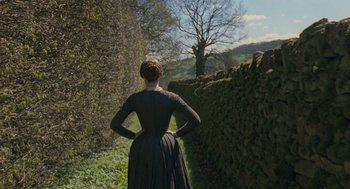 Movie still from “Jane Eyre” (2011), directed by Cary Joji Fukunaga – A woman standing in front of a hedge; Wide shot, Over the shoulder angle