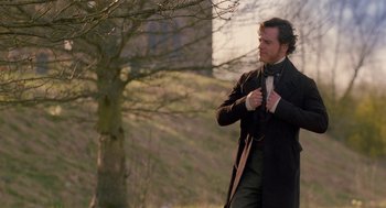 Movie still from “Jane Eyre” (2011), directed by Cary Joji Fukunaga – A man standing in a field wearing a coat and tie; Medium shot, Over the shoulder angle