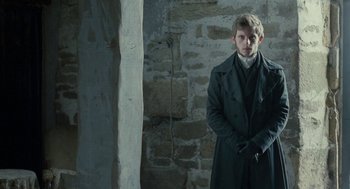 Movie still from “Jane Eyre” (2011), directed by Cary Joji Fukunaga – A man in a trench coat standing in front of a brick wall; Medium shot, Low angle