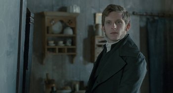 Movie still from “Jane Eyre” (2011), directed by Cary Joji Fukunaga – A man in a suit standing in front of a shelf; Medium shot, Over the shoulder angle