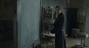 Movie still from “Jane Eyre” (2011), directed by Cary Joji Fukunaga – A man standing in front of an easel in front of a chalkboard; Medium shot, Over the shoulder angle