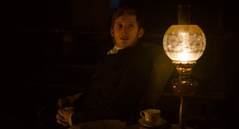 Movie still from “Jane Eyre” (2011), directed by Cary Joji Fukunaga – A man sitting in front of a lamp in a dark room; Medium shot, Over the shoulder angle