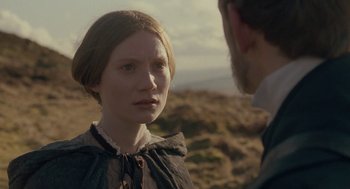 Movie still from “Jane Eyre” (2011), directed by Cary Joji Fukunaga – A woman in a dress standing next to a bearded man; Close Up shot, Over the shoulder angle