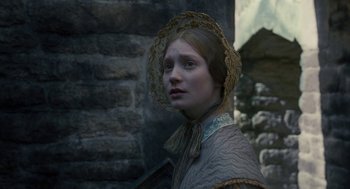 Movie still from “Jane Eyre” (2011), directed by Cary Joji Fukunaga – A young woman wearing an old - fashioned dress and a hat; Close Up shot, Over the shoulder angle