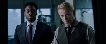 Movie still from “Jigsaw” (2017), directed by Michael Spierig – A man in a suit and tie standing next to another man in a suit and tie; Close Up shot, Over the shoulder angle