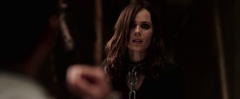 Movie still from “Jigsaw” (2017), directed by Michael Spierig – A woman with a chain around her neck looking into the camera; Close Up shot, Over the shoulder angle