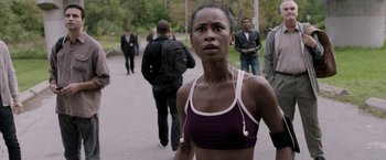 Movie still from “Jigsaw” (2017), directed by Michael Spierig – A woman in a purple and white sports bra; Medium shot, Over the shoulder angle
