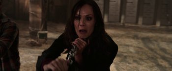 Movie still from “Jigsaw” (2017), directed by Michael Spierig – A woman in a black shirt is holding a gun; Close Up shot, High angle