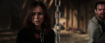 Movie still from “Jigsaw” (2017), directed by Michael Spierig – A woman in a black shirt is chained up; Close Up shot, Over the shoulder angle