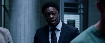 Movie still from “Jigsaw” (2017), directed by Michael Spierig – A man wearing a suit and tie in front of a building; Close Up shot, Over the shoulder angle