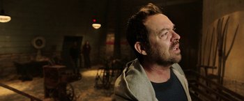 Movie still from “Jigsaw” (2017), directed by Michael Spierig – A man with a beard is looking into the distance; Close Up shot, Over the shoulder angle