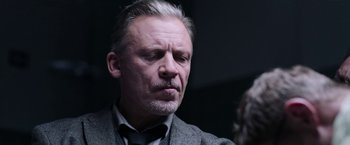 Movie still from “Jigsaw” (2017), directed by Michael Spierig – An older man in a suit and bow tie; Close Up shot, Over the shoulder angle