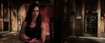 Movie still from “Jigsaw” (2017), directed by Michael Spierig – A woman in a black dress holding a red object; Medium shot, Over the shoulder angle