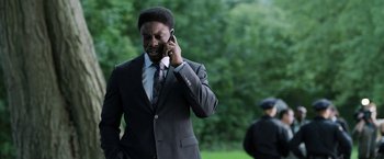 Movie still from “Jigsaw” (2017), directed by Michael Spierig – A man in a suit and tie talking on a cell phone; Close Up shot, Over the shoulder angle
