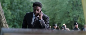 Movie still from “Jigsaw” (2017), directed by Michael Spierig – A man in a suit and tie talking on a cell phone; Close Up shot, Over the shoulder angle