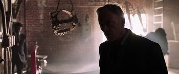 Movie still from “Jigsaw” (2017), directed by Michael Spierig – A man in a suit and tie in front of a brick wall; Medium shot, Low angle