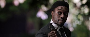 Movie still from “Jigsaw” (2017), directed by Michael Spierig – A man in a suit holding a magnifying glass in his hand; Close Up shot, Over the shoulder angle