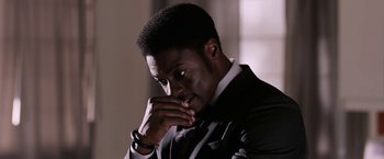 Movie still from “Jigsaw” (2017), directed by Michael Spierig – A man in a black suit and white shirt is holding his hand to his face; Close Up shot, Over the shoulder angle