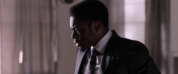 Movie still from “Jigsaw” (2017), directed by Michael Spierig – A man in a suit and tie looking to his left; Close Up shot, Low angle