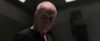 Movie still from “Jigsaw” (2017), directed by Michael Spierig – An old man with a shaved head and a black shirt; Close Up shot, Low angle