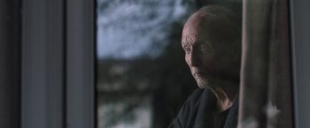 Movie still from “Jigsaw” (2017), directed by Michael Spierig – An old man with a beard is looking out a window; Close Up shot, Low angle
