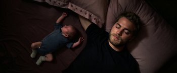 Movie still from “Jigsaw” (2017), directed by Michael Spierig – A man sleeping next to a baby on a bed; Close Up shot, Overhead angle