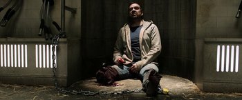 Movie still from “Jigsaw” (2017), directed by Michael Spierig – A man sitting on the ground holding a knife; Medium shot, High angle