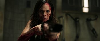 Movie still from “Jigsaw” (2017), directed by Michael Spierig – A woman with blood on her face holding a gun; Close Up shot, Over the shoulder angle