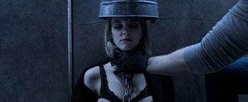 Movie still from “Jigsaw” (2017), directed by Michael Spierig – A woman in a black bra is chained to a metal bucket on her head; Close Up shot, Overhead angle