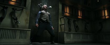 Movie still from “Jigsaw” (2017), directed by Michael Spierig – A man standing in front of a building with a camera hanging from the ceiling; Wide shot, Low angle