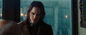 Movie still from “John Carter” (2012), directed by Andrew Stanton – A man with long black hair wearing a brown coat; Close Up shot, Low angle