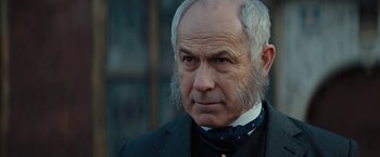 Movie still from “John Carter” (2012), directed by Andrew Stanton – An older man in a black suit and a white beard; Close Up shot, Over the shoulder angle