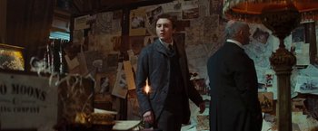 Movie still from “John Carter” (2012), directed by Andrew Stanton – A man in a suit and tie in front of a wall covered with papers; Medium shot, Over the shoulder angle