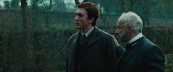 Movie still from “John Carter” (2012), directed by Andrew Stanton – A man in a suit and tie standing next to another man in a suit; Close Up shot, Over the shoulder angle