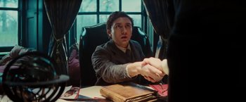 Movie still from “John Carter” (2012), directed by Andrew Stanton – A man sitting at a table shaking hands with another man; Medium shot, Over the shoulder angle