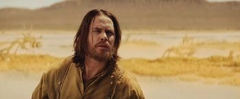 Movie still from “John Carter” (2012), directed by Andrew Stanton – A man with long brown hair and a beard is standing outside; Close Up shot, Over the shoulder angle