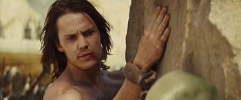 Movie still from “John Carter” (2012), directed by Andrew Stanton – A shirtless man leaning against a rock with his hands on the wall; Close Up shot, Over the shoulder angle