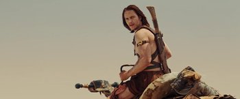 Movie still from “John Carter” (2012), directed by Andrew Stanton – A man with a sword sitting on top of a motorcycle; Medium shot, Low angle